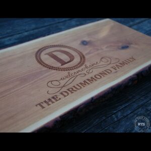 Live edge wood serving board with regal welcome home design engraved.