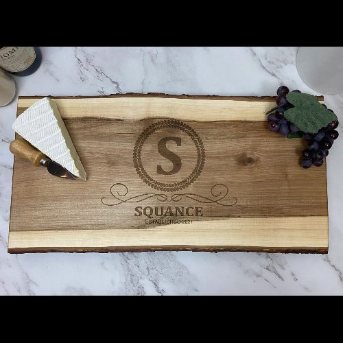 Live edge serving board with initial, name and date engraved in the center.