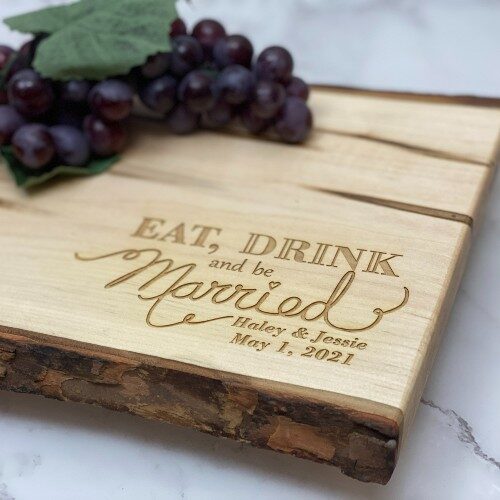 Eat, drink and be married engraved in the corner of a live edge serving board.