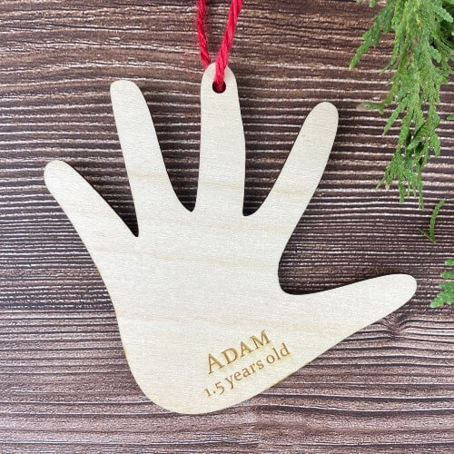 A handprint ornament made from a tracing of a child's hand, engraved with their name and age.