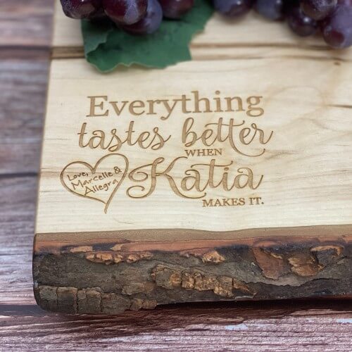 Wooden charcuterie board with "everything tastes better with makes it," engraved.
