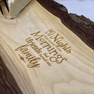 Live edge charcuterie board with "here's to the nights that turned into mornings with friends that turned into family" engraved on it.