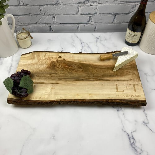 A wood serving board engraved for a wedding with the couples initials and wedding date.